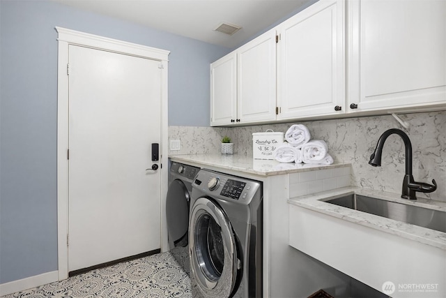 laundry area featuring cabinet space, visible vents, baseboards, washing machine and dryer, and a sink