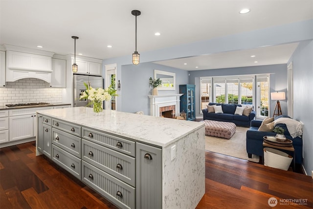 kitchen with stainless steel appliances, dark wood-type flooring, and light stone counters