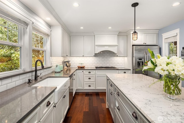 kitchen featuring light stone countertops, dark wood-type flooring, stainless steel appliances, and a sink