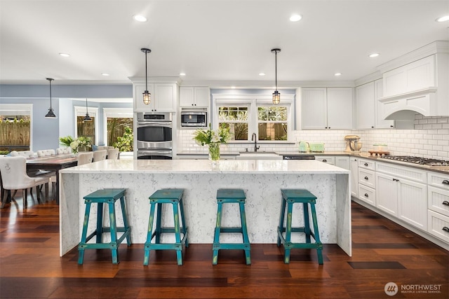 kitchen featuring appliances with stainless steel finishes, a sink, a breakfast bar area, and light stone countertops