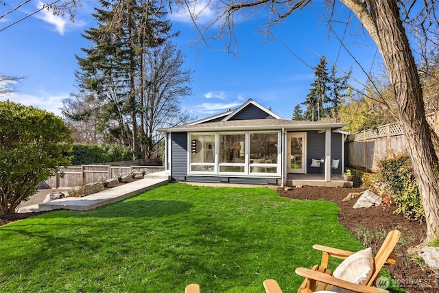 back of house with a lawn and a fenced backyard