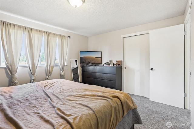 carpeted bedroom with a textured ceiling and a closet