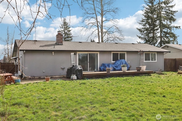 rear view of property with a yard, a chimney, fence, and a wooden deck