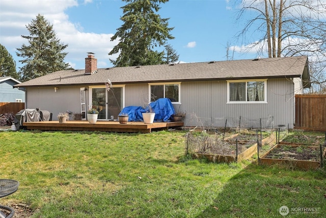 rear view of property featuring a lawn, a chimney, fence, and a garden