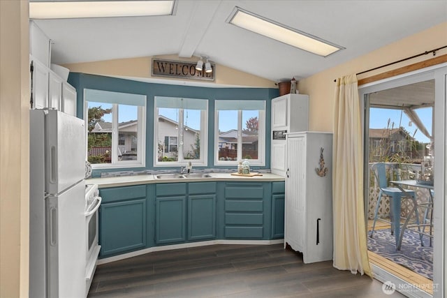 kitchen featuring white appliances, dark wood-style floors, vaulted ceiling with beams, light countertops, and a sink