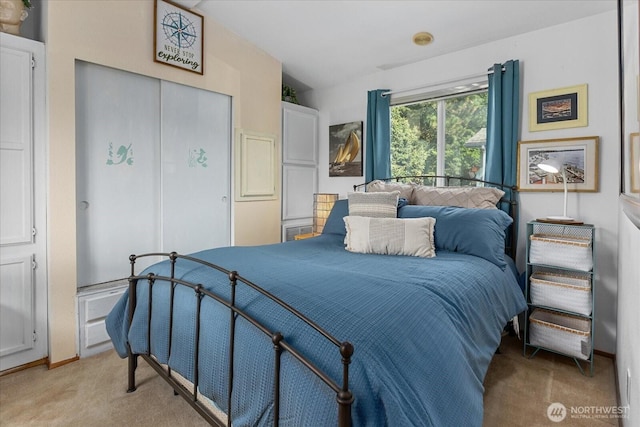 bedroom featuring light carpet, vaulted ceiling, a closet, and baseboards