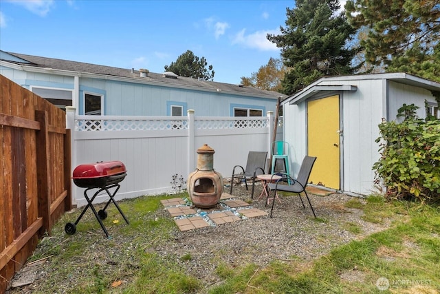 view of yard featuring a fenced backyard, a fire pit, an outdoor structure, a shed, and a patio area