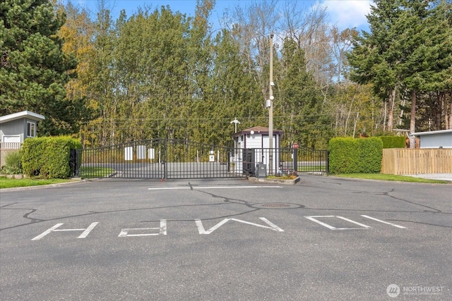 view of vehicle parking with fence and a gate