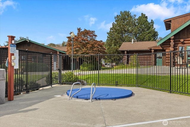 view of swimming pool featuring fence and a lawn