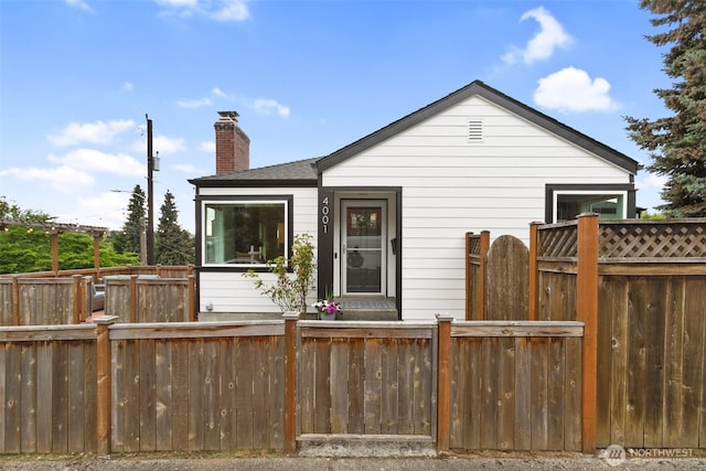 view of front of home featuring fence private yard, a chimney, and a shingled roof