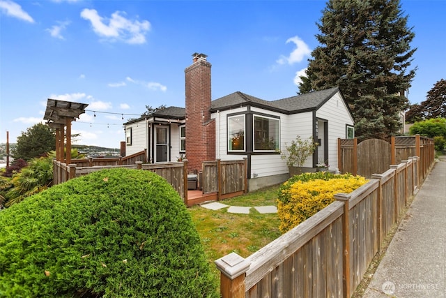 view of side of home featuring a gate, fence, a wooden deck, a shingled roof, and a chimney