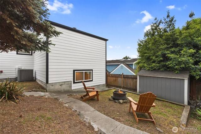 view of yard with a shed, fence, cooling unit, a fire pit, and an outdoor structure