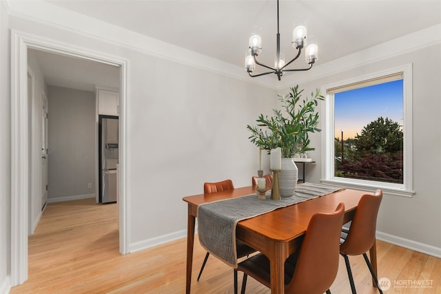 dining space with a notable chandelier, light wood-style flooring, and baseboards