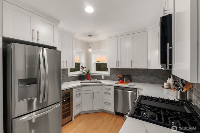 kitchen featuring white cabinets, light stone counters, beverage cooler, and appliances with stainless steel finishes