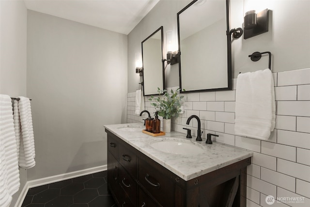 bathroom featuring a sink, baseboards, double vanity, and tile patterned floors