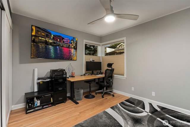 office space with baseboards, light wood-style floors, and a ceiling fan