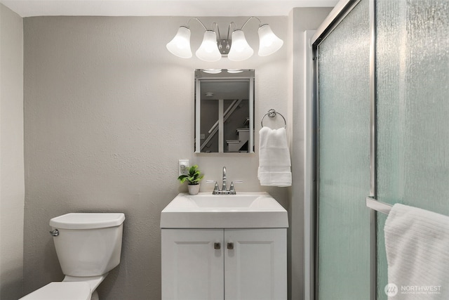 full bathroom with vanity, toilet, a shower stall, and a textured wall