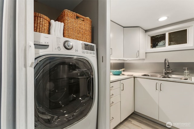 clothes washing area featuring washer / dryer, light wood-style flooring, recessed lighting, cabinet space, and a sink