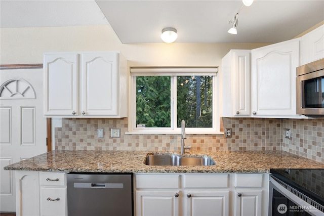 kitchen with stainless steel appliances, backsplash, a sink, and white cabinetry