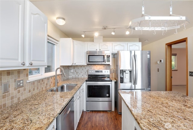 kitchen featuring stainless steel appliances, tasteful backsplash, white cabinets, a sink, and light stone countertops