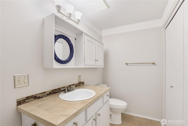 bathroom with toilet, vanity, visible vents, and baseboards