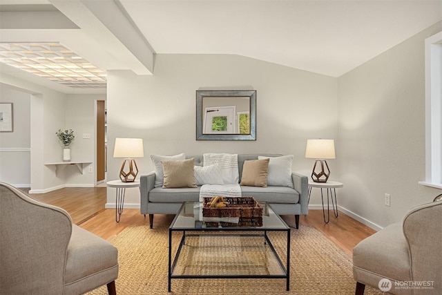 living area featuring vaulted ceiling, baseboards, and light wood-style floors