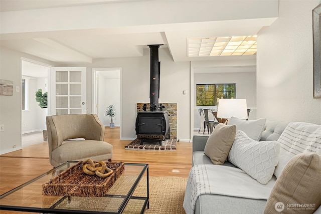 living room featuring light wood finished floors, a wood stove, and baseboards