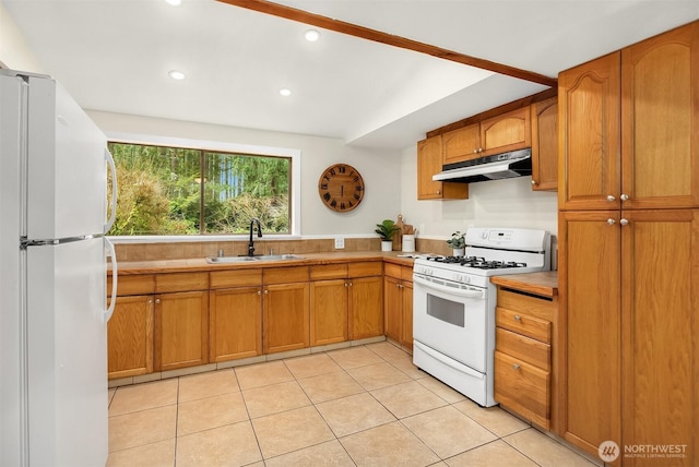 kitchen featuring white appliances, brown cabinetry, a sink, and under cabinet range hood