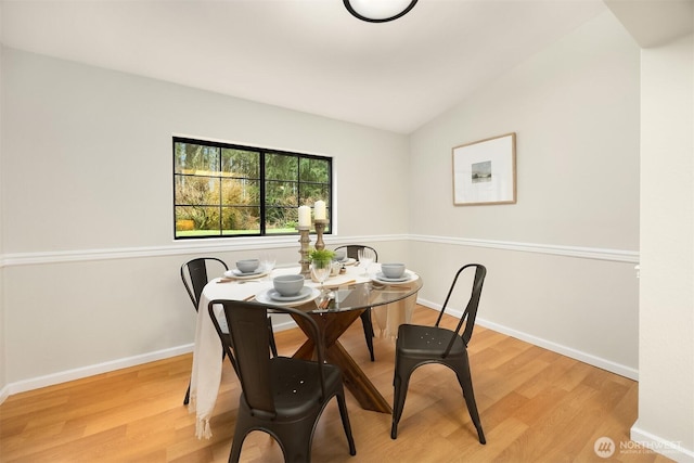 dining room with baseboards, vaulted ceiling, and wood finished floors