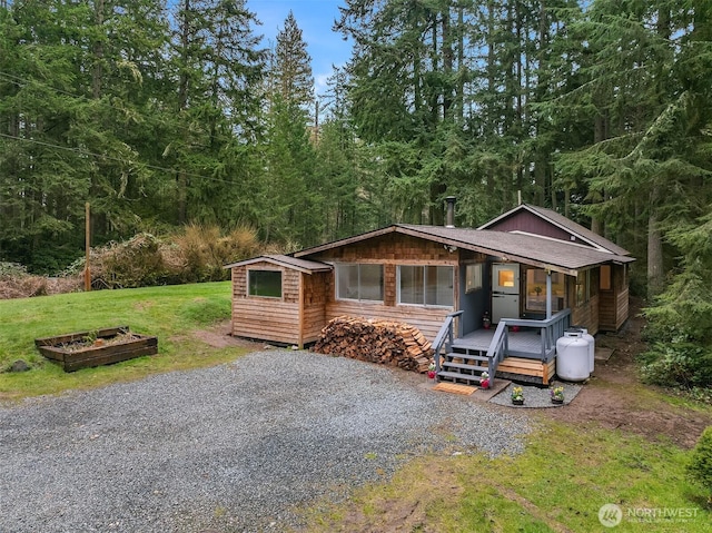 view of front of house with gravel driveway and a front lawn