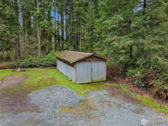 view of outdoor structure with a wooded view and an outbuilding