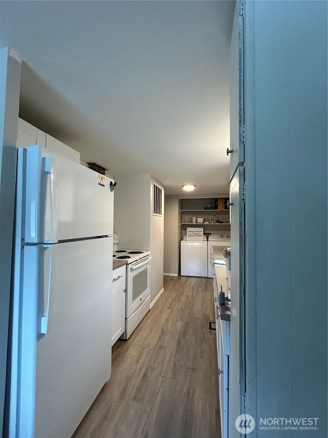 kitchen featuring visible vents, white cabinets, wood finished floors, white appliances, and independent washer and dryer