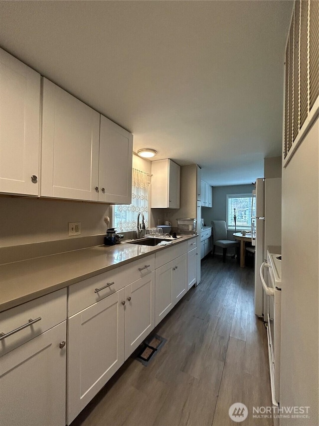 kitchen featuring dark wood-style flooring, a sink, white electric range oven, and white cabinetry