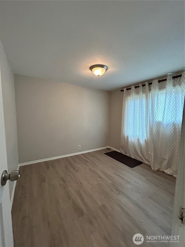 unfurnished room with baseboards and wood finished floors