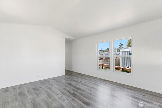 unfurnished room with wood finished floors and vaulted ceiling