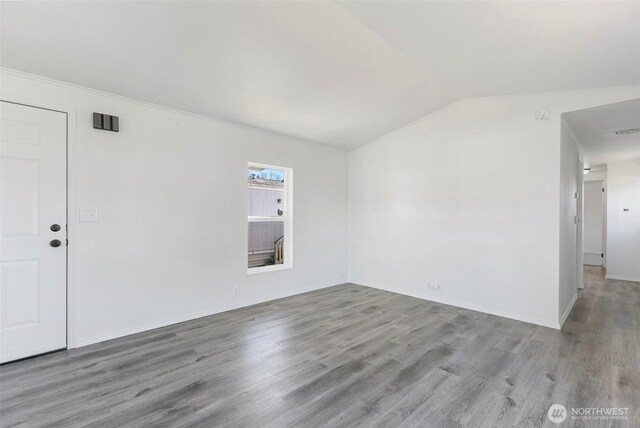 empty room with lofted ceiling, wood finished floors, and ornamental molding