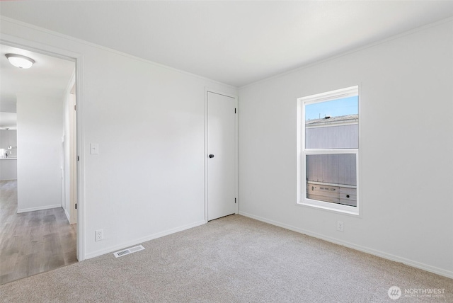 spare room with visible vents, baseboards, and carpet