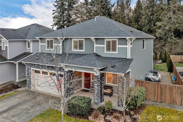 view of front of property with a patio, an attached garage, a shingled roof, fence, and concrete driveway