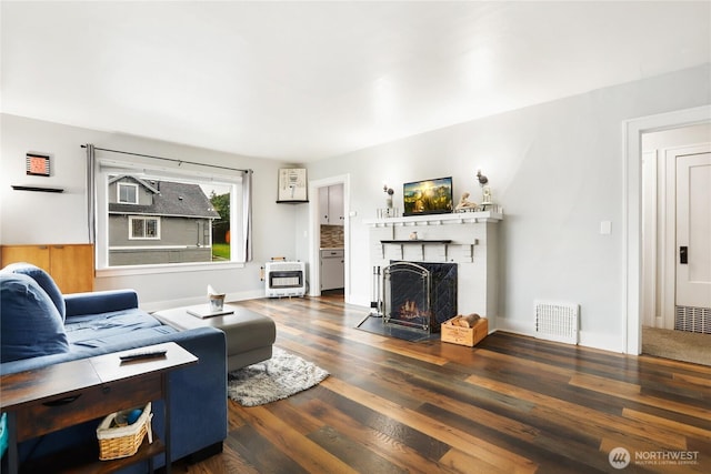 living room with a fireplace, wood finished floors, visible vents, and heating unit