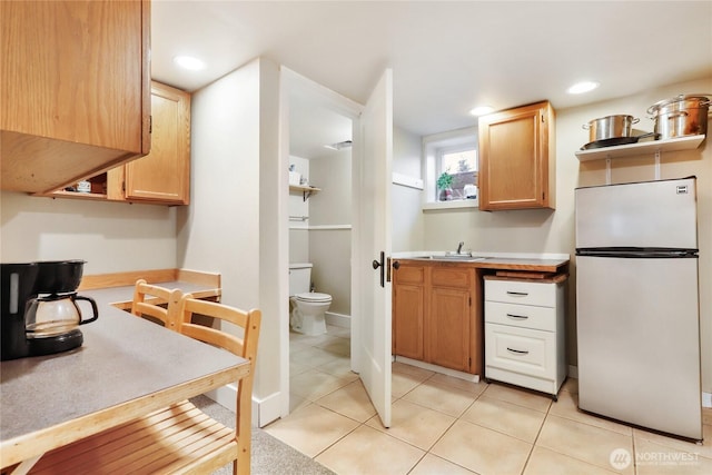 kitchen with light tile patterned floors, freestanding refrigerator, light countertops, a sink, and recessed lighting