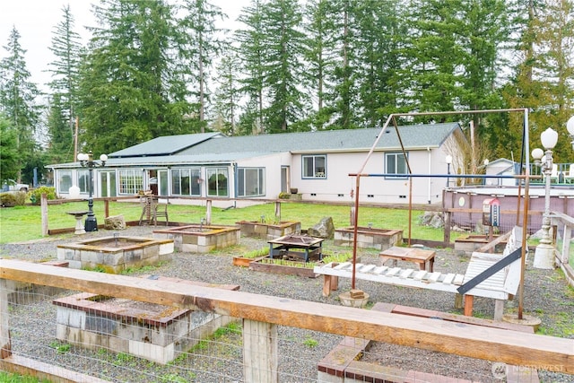 back of house featuring crawl space, a garden, and a lawn