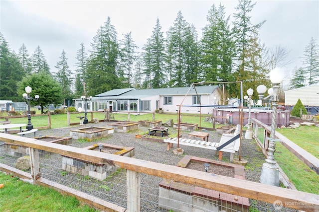 back of property with an outdoor fire pit, a garden, and a lawn