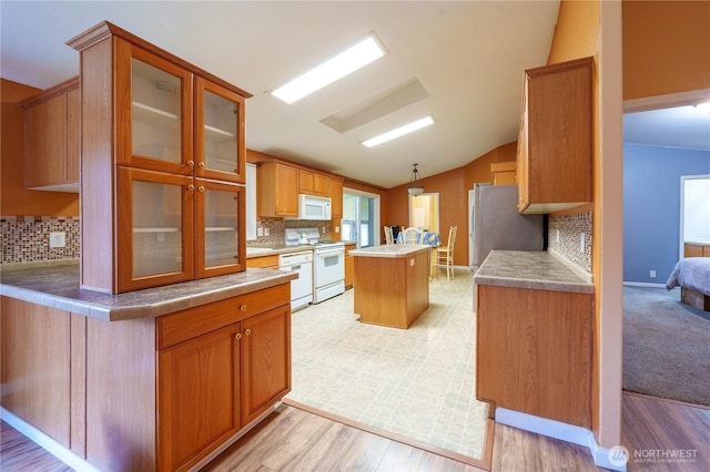 kitchen featuring white appliances, decorative backsplash, glass insert cabinets, a center island, and vaulted ceiling