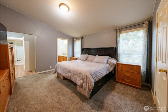 carpeted bedroom featuring lofted ceiling, connected bathroom, and baseboards