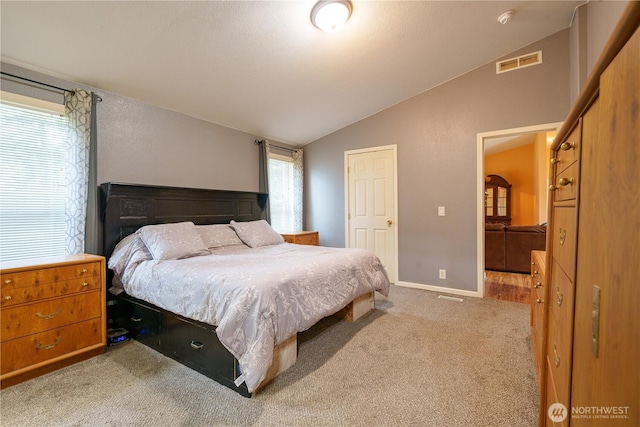 carpeted bedroom with visible vents, vaulted ceiling, and baseboards