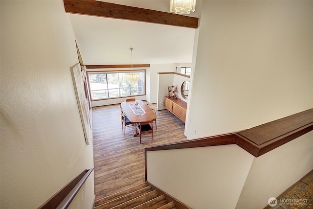 stairway with vaulted ceiling with beams, a chandelier, and wood finished floors