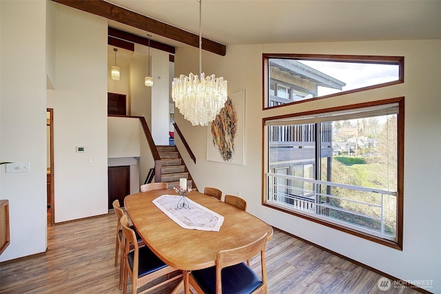 dining area with stairway, a chandelier, wood finished floors, and beamed ceiling