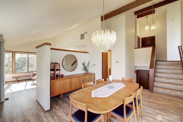 dining room with an inviting chandelier, stairs, vaulted ceiling, and wood finished floors