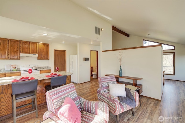 kitchen featuring white appliances, visible vents, brown cabinetry, light countertops, and light wood-style floors