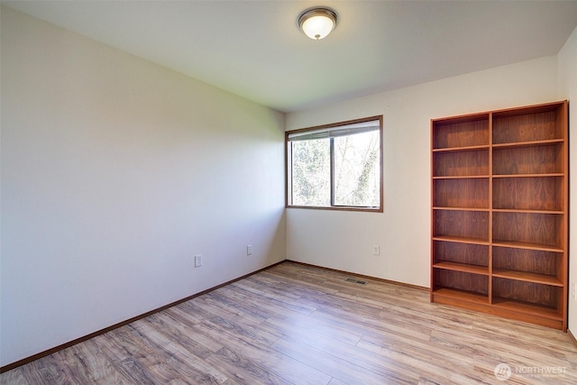 empty room with visible vents, baseboards, and wood finished floors